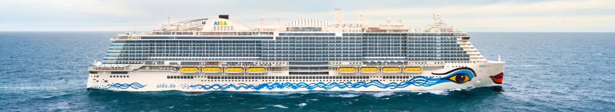 Die AIDAcosma von der Seite auf hoher See an einem bewölkten Tag.