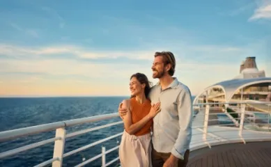 Januarkampagne 2026 Ein Paar steht Arm in Arm auf dem Außendeck der Mein Schiff Flow und schaut auf den Horizont.