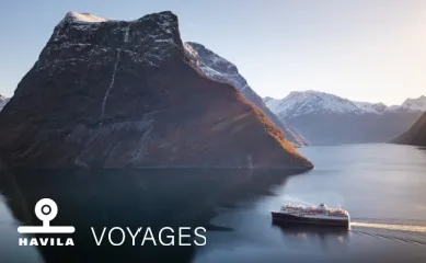 Eines der Havila Voyages Schiffe fährt bei Sonnenschein durch den Hjørundfjord in Norwegen. ©Oclin