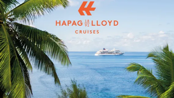 Hapag-Lloyd Cruises Schiff auf ruhigem türkisblauen Meer, gerahmt von tropischen Palmen