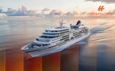 Die MS EUROPA von Hapag-Lloyd Cruises fährt in der Dämmerung über ruhiges Meer, Luftaufnahme.