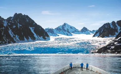 Naturwunder hautnah – Mit Hapag-Lloyd Cruises im ewigen Eis Einblick vom Schiffsbug auf ein beeindruckendes Panorama aus Gletschereis und schroffen Berggipfeln unter strahlend blauem Himmel.