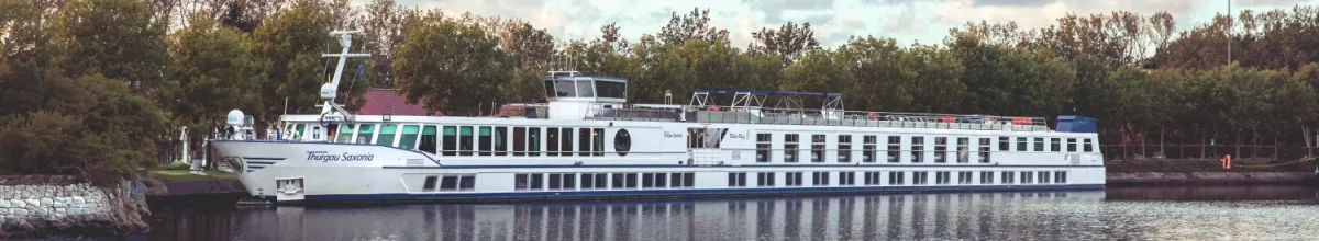 Die Thurgau Saxonia auf dem Fluss aus der Seitenansicht fotografiert, im Hintergrund grüne Wälder.