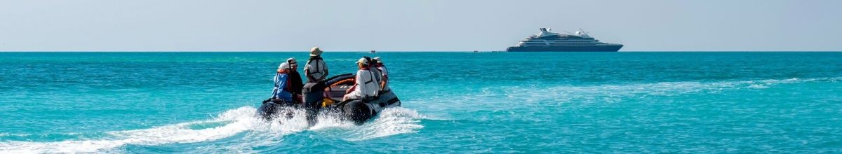 Drei Personen bei den Lacepede Islands auf einem Schlauchboot fahren auf ein PONANT Schiff zu. ©StudioPONANT-Laure Patricot