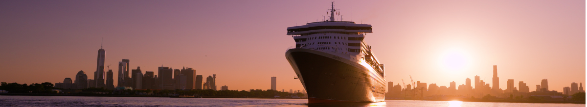 Die Queen Mary 2, wie sie in der Abendsonne den Hafen von New York verlässt. Im Hintergrund die Skyline von Manhattan.