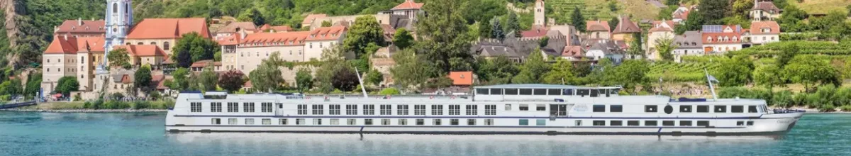 Das Schiff MS VistaClassica fährt den Fluss entlang und im Hintergrund zeichnet sich eine Stadt ab.