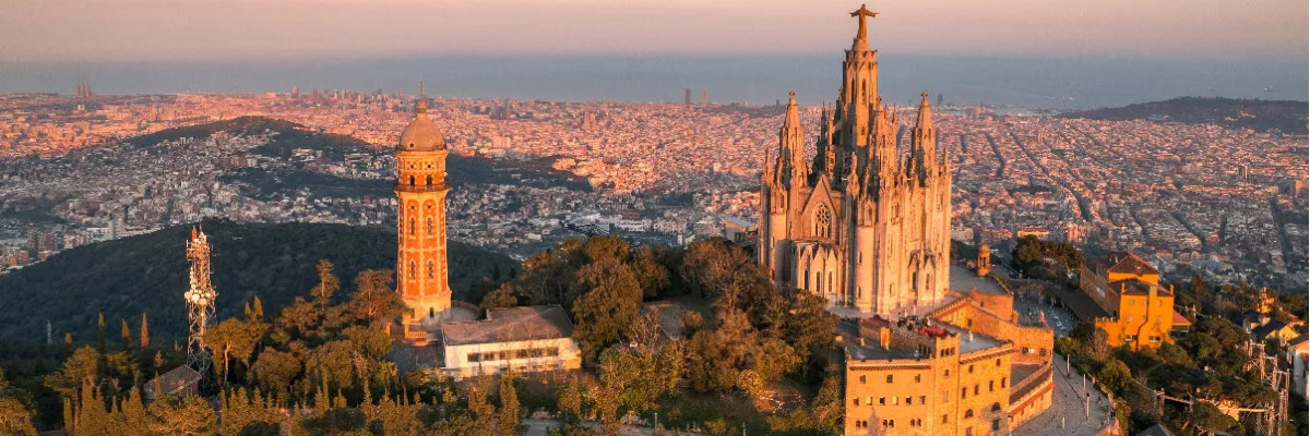 Mediterranes Lebensgefühl: Entdecken Sie Barcelona und die Schätze des Mittelmeers im Sommer 2026 Panorama-Blick über Barcelona bei Sonnenuntergang mit der Sagrat Cor Kirche auf dem Tibidabo im Vordergrund – ein kulturelles Highlight der Mittelmeer-Routen.