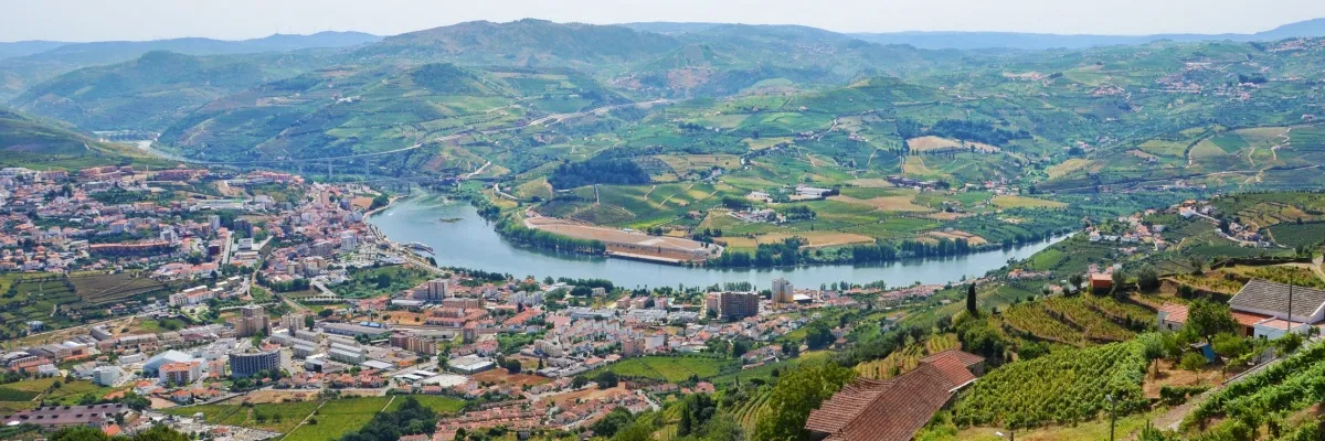 Luftbild von Peso da Regua inmitten der Weinberge von Alto Douro, dem ältesten Weinbaugebiet der Welt. In der Bildmitte schlängelt sich der Douro durch die Stadt.