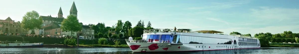 Ein A-ROSA Schiff auf der Rhône. Im Hintergrund sind die Türme einer Kirche sowie Häuser und Bäume zu sehen.