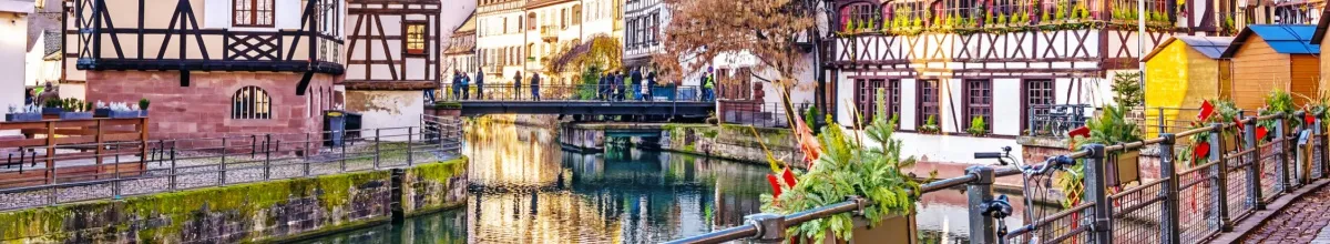 Blick über den Fluss in Straßburg, auf den beiden Seiten stehen wunderschöne Häuser und rects befindet sich die Brücke.