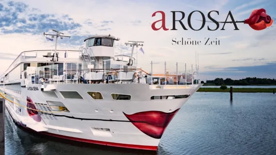 Frontansicht von A-ROSA SENA auf dem Fluss. Im Hintergrund ist ein bewaldetes Ufer zu sehen. Rechts oben das A-ROSA Logo in schwarz und rot.