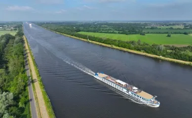 Die MS VIVA Ruby auf einer Flusskreuzfahrt auf der Mosel entlang grüner Felder und Wiesen.