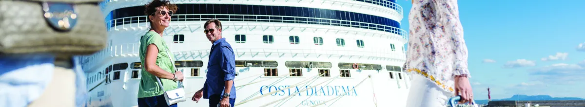 Passagiere vor dem Kreuzfahrtschiff Costa Diadema im Hafen bei blauem Himmel.