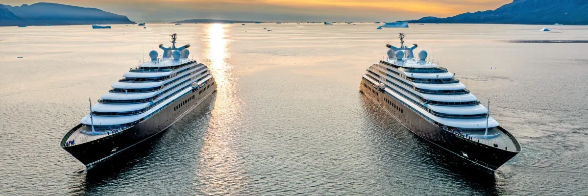 Zwei Yachten von Scenic Luxury Cruises nebeneinander auf dem Wasser bei Sonnenuntergang.