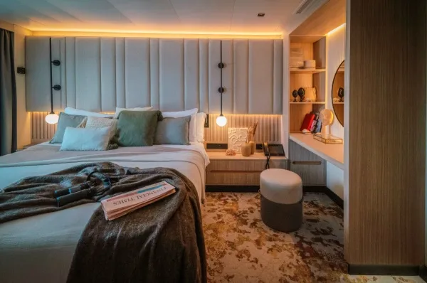 Eine moderne Kabine auf der SH Diana von Swan Hellenic mit gemütlichem Licht, einem Doppelbett und Schminktisch.