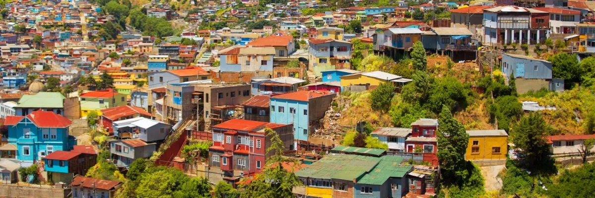 Mit Swan Hellenic nach Lateinamerika 2026 Viele bunte Häuser auf einer begrünten Anhöhe in Valparaiso in Chile an einem sommerlichen Tag.