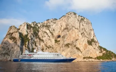 eine Yacht von SeaDream Yacht Club vor einem gewaltigen Felsen im Ozean.