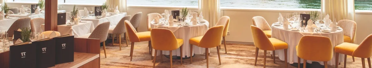Gelbe Stühle und runde Restauranttische an Bord der MS Thurgau Gold.