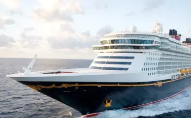 Die Disney Dream in der Vorderansicht in voller Fahrt auf See. Im Hintergrund schweben vereinzelte Wolken. ©Disney