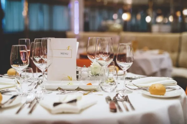 Ein Tisch im Restaurant an Bord schön eingedeckt mit Weingläsern, Besteck und weißen Stoffservietten.