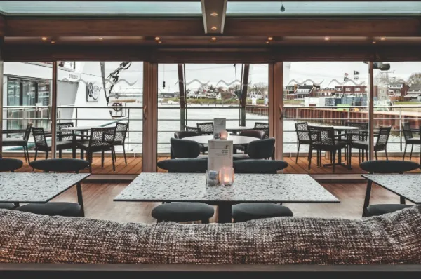 MS Swiss Pearl Bordleben Bar mit bequemen Sitzmöbeln und Tischen und Blick auf das Sonnendeck an Bord der MS Swiss Pearl.