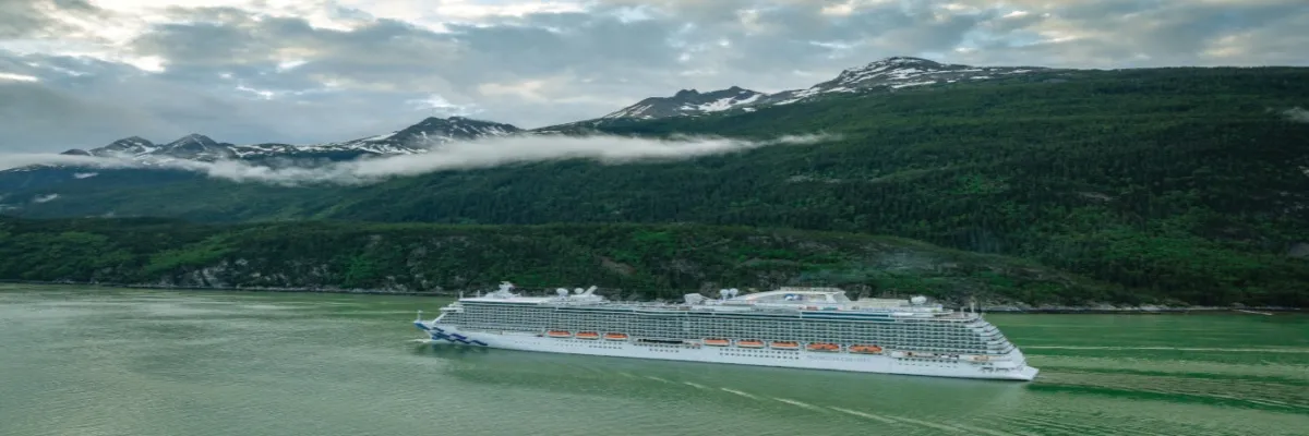 Das Schiff Majestic Pincess gleitet im Wasser und Alaska ist im Hintergrund zu sehen.