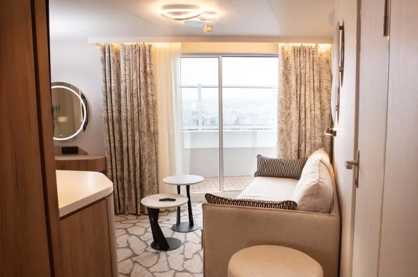 Die Grand Horizon Suite auf der Celestyal Discovery mit Panorama Fenstern, einem Sofa und Schminktisch.