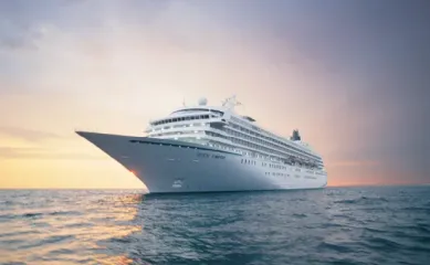 Die Crystal Symphony auf offener See in einem sanften Sonnenuntergang, der sich auch im Meer spiegelt.