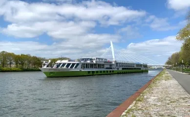 Das Schiff DCS Amethyst 2 fährt einen Kanal entlang, fotografiert vom gepflasterten Ufer.