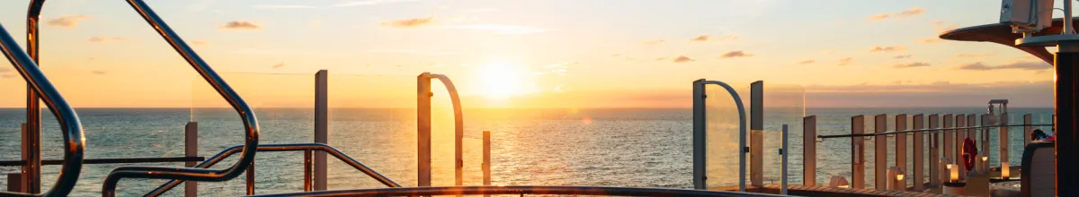 AIDA Buchungsstart Sommer 2028 – Ihr Logenplatz am Meer Goldener Sonnenuntergang über dem offenen Meer, fotografiert vom Außendeck eines AIDA Kreuzfahrtschiffes. Im Vordergrund sind moderne Reling-Elemente und die warme Lichtstimmung auf dem Pooldeck zu sehen, die Fernweh nach der Sommersaison 2028 weckt.