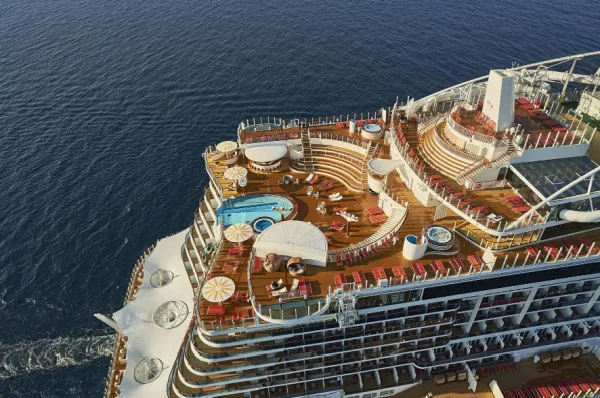 Luxuriöse Entspannung auf AIDAcosma – Highlights der Sommersaison 2028 Beeindruckende Luftaufnahme des Hecks von AIDAcosma. Zu sehen sind die weitläufigen Außendecks mit Infinity-Pools, zahlreichen Sonnenliegen unter weißen Schirmen und das tiefblaue Meer während der Fahrt.