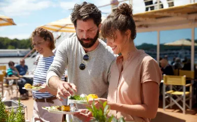 Gäste genießen das Buffet auf dem Sonnendeck eines A-ROSA Schiffes bei Sonnenschein während des Oster-Specials 2026.