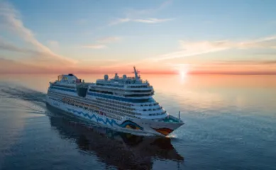 Kreuzfahrtschiff von AIDA Cruises auf offener See vor einem farbenfrohen Abendhimmel für die Reisesaison 2027.