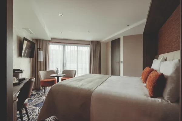Kabine an Bord der MS Voyage mit Panoramafenster, zwei Stühlen und einem Doppelbett.