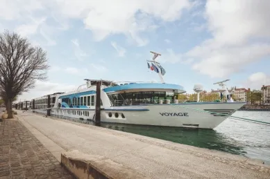 Die MS Voyage an einem Bootsanleger am Fluss bei gutem Wetter.