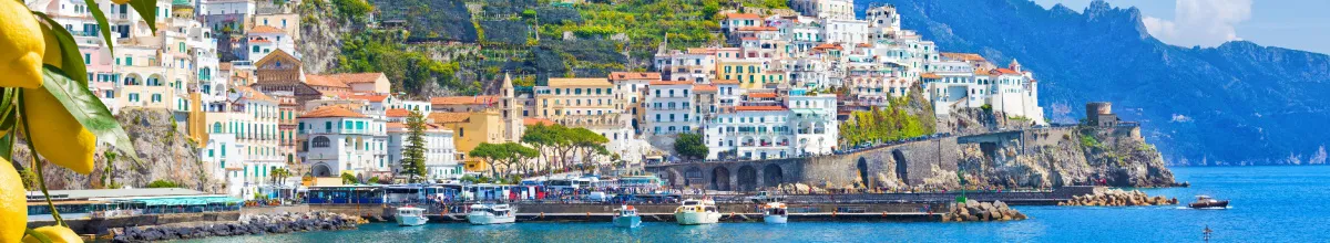 Panorama-Ansicht einer malerischen Küstenstadt am Mittelmeer mit Zitronen im Vordergrund – Inspiration für die Route Mediterrane Schätze.