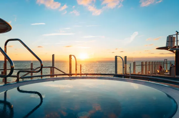 Entspannung im Whirlpool auf dem AIDA Deck bei Sonnenuntergang während einer Fernreise mit gratis Internet-Flat.