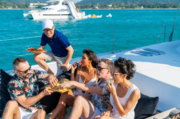 Eine Gruppe von Gästen genießt gemeinsam Obst und Snacks auf dem Deck eines Schiffes – moderne Kreuzfahrt-Etikette und Lifestyle.