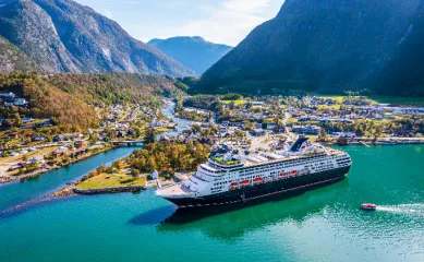 Das Kreuzfahrtschiff VASCO DA GAMA von nicko cruises in einem malerischen norwegischen Fjord vor grüner Bergkulisse – Ein Highlight der Nordkap-Kreuzfahrt 2026 zum Duo-Deal-Vorteilspreis.