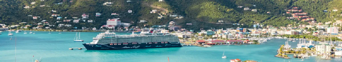 Panorama-Aufnahme der <em>Mein Schiff Flow</em> in einer malerischen Bucht mit türkisfarbenem Wasser – entdecken Sie die neuen Winterrouten 2026/27 im Mittelmeer und Westeuropa.