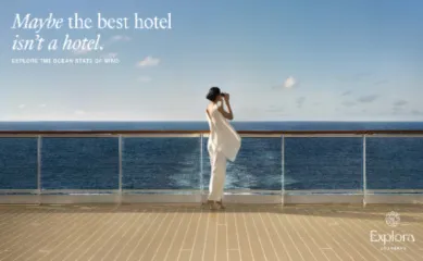 Eine elegante Frau in weißer Kleidung genießt den Ocean State of Mind an Bord von Explora Journeys mit Blick auf den weiten, blauen Ozean.
