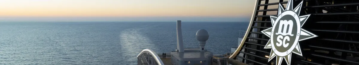 Schornstein eines MSC Cruises Kreuzfahrtschiffs mit MSC-Logo am Heck und Blick auf das weite, ruhige Meer.