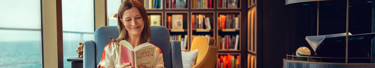 Die schiffseigene Cunard Bibliothek Eine Frau in der Bibliothek auf einem Cunard Schiff, die Jane Austen liest, links sieht man das Meer.