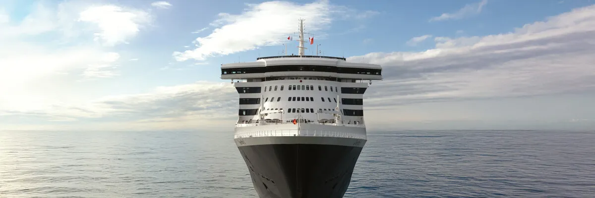Eleganz auf den Weltmeeren – Cunard Frühbucherangebote 2028/2029 Symmetrische Frontalansicht eines eleganten Cunard-Luxusschiffs, das auf dem ruhigen, tiefblauen Ozean direkt auf den Betrachter zufährt.