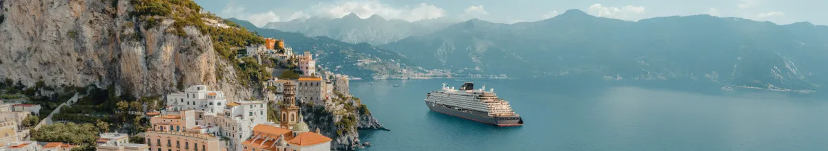 Das luxuriöse Kreuzfahrtschiff von Explora Journeys fährt entlang der malerischen Steilküste der Amalfiküste mit historischen, bunten Häusern.