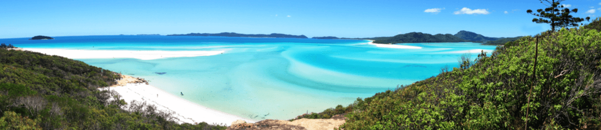 Der Whitehaven Beach liegt vor tropischen Wäldern und beeindruckt mit märchenhaften Verwirbelungen von Wasser und weißem Sand.
