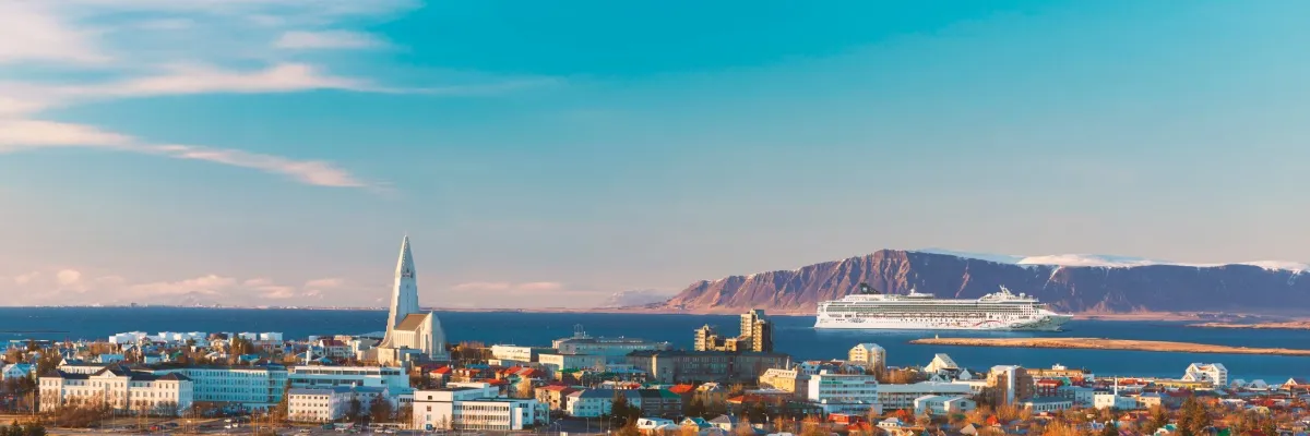 Die Norwegian Star vor Reykjavik. Links ist die markante Hallgrímskirkja zu sehen, rechts erhebt sich hinter dem Schiff ein gewaltiges Felsmassiv.