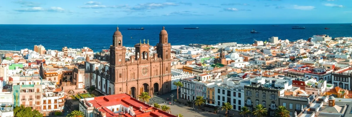 Jetzt buchen und 100 € Rabatt auf Ihre Kanaren-Kreuzfahrt sichern Blick über die Altstadt von Las Palmas de Gran Canaria mit der Kathedrale Santa Ana im Zentrum und dem Atlantik im Hintergrund.