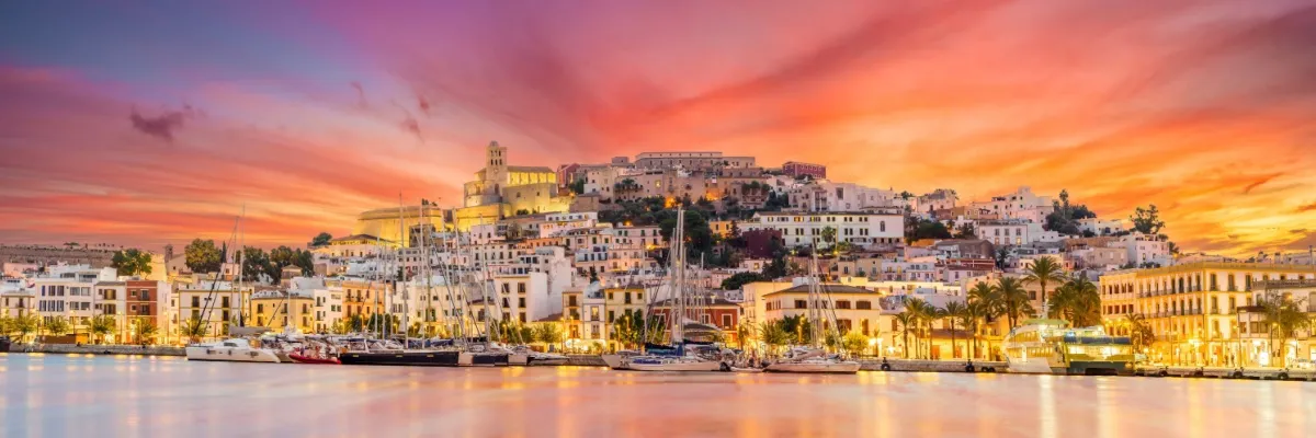 Sichern Sie sich jetzt 100 € Rabatt für Ihre Costa Kreuzfahrt ins Mittelmeer Ibiza-Stadt vom Meer aus gesehen im Sonnenuntergang.