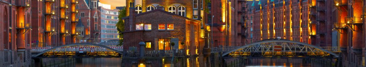 Die stimmungsvoll beleuchtete Hamburger Speicherstadt bei Abenddämmerung mit historischen Backsteingebäuden, Brücken und Kanälen als idealer Starthafen.